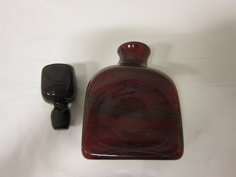 Karaffe mit Stöpsel, von Holmegaard, Dänemark 
Unika Karaffe aus kräftigem, schönem gepustetem Glas in einer 
dunkel-bernsteinfarbigen Farbe und rot/lila "Flammen"-Farbe
Produktion: 1965
Design: Per Lütken
Aus der Lava-Serie aber selten als Karaffe