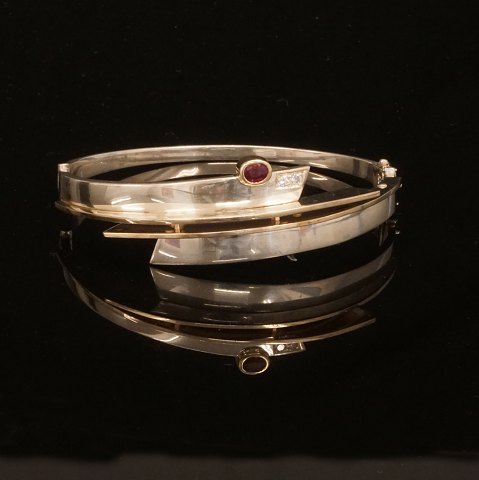 A 14kt gold and sterlingsilver bangle with two 
diamonds of ca. 0,08ct. Size: 6,6x6cm