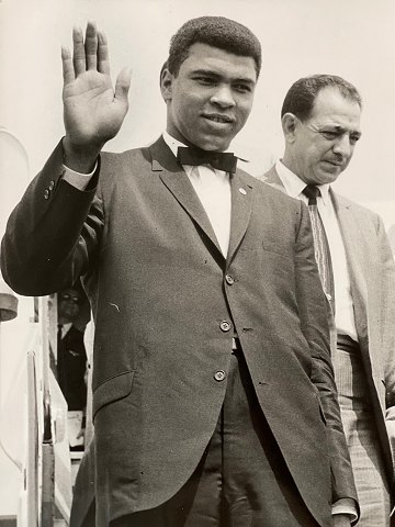 Vintage Pressefoto des Boxers Muhammad Ali / Cassius Clay (1942 - 2016), der bei 
der Ankunft am Londoner Flughafen für den Kampf gegen Henry Cooper im Jahr 1966 
winkt