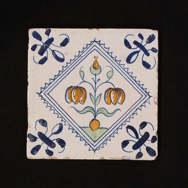 A 17th century polychrome decorated Dutch tile with flowers. Circa 1620-40. 
Size: 13x13cm